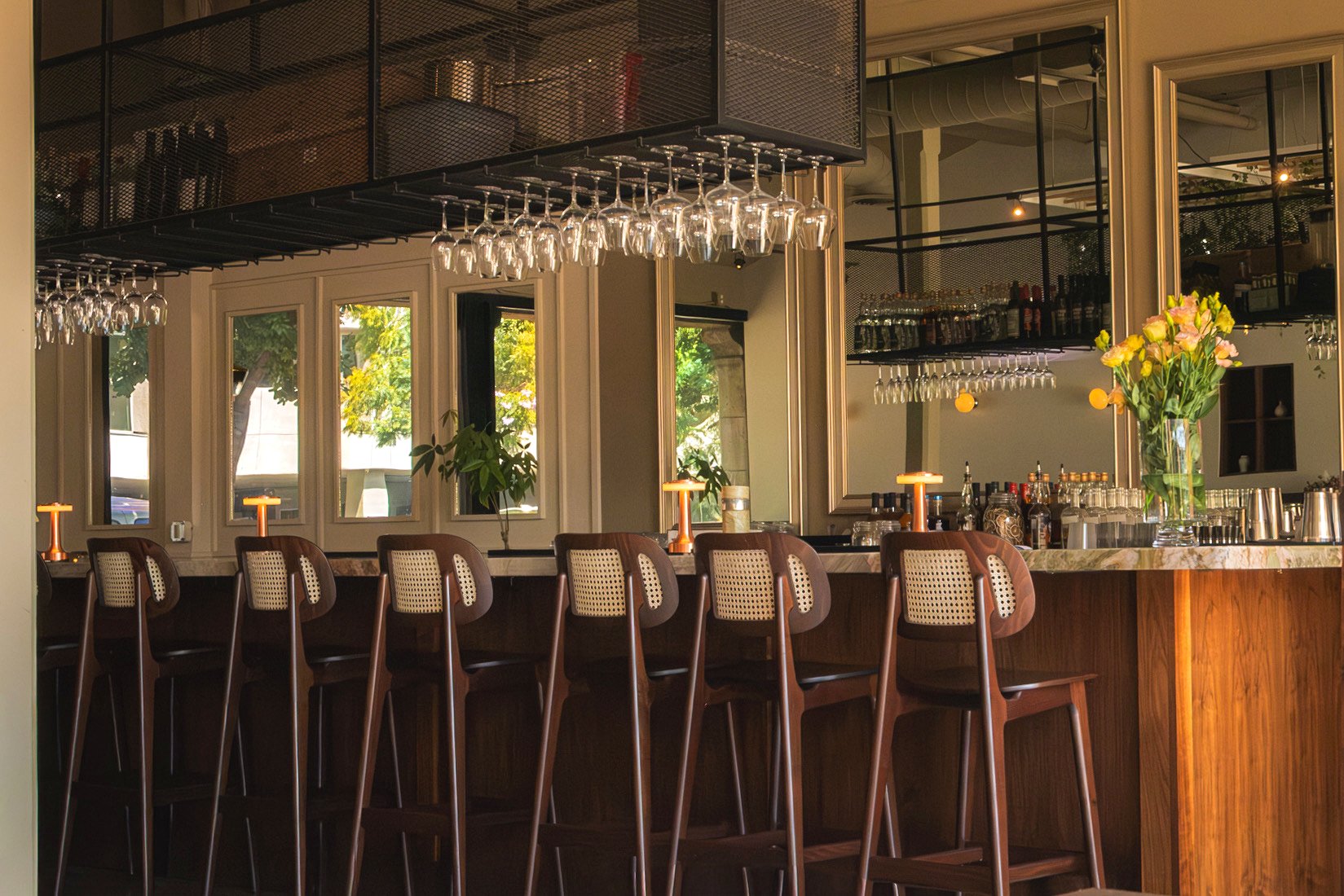 The Danbi bar: cane stools, hanging glassware, fresh flowers and warm lamplight